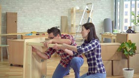 O casal novo recolhe uma tabela de cabeceira em um apartamento moderno novo O casal novo recolhe uma tabela de cabeceira em um apartamento moderno novo