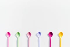 O conceito de colheres de sobremesa coloridas no fundo branco imagem de stock O conceito de colheres de sobremesa coloridas no fundo branco imagem de stock