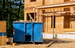 O contentor, recicla escaninhos do desperd?cio e de lixo perto do canteiro de obras novas da constru??o de casas do apartamento fotografia de stock O contentor, recicla escaninhos do desperd?cio e de lixo perto do canteiro de obras novas da constru??o de casas do apartamento fotografia de stock