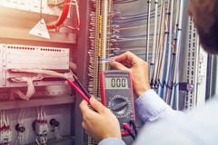 O coordenador testa o armário bonde industrial Fio à disposição do eletricista com multímetro Profissional no painel de controle fotografia de stock royalty free O coordenador testa o armário bonde industrial Fio à disposição do eletricista com multímetro Profissional no painel de controle fotografia de stock royalty free