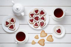 O coração deu forma a cookies para o dia de Valentim com bule e dois copos do chá no fundo de madeira branco fotos de stock O coração deu forma a cookies para o dia de Valentim com bule e dois copos do chá no fundo de madeira branco fotos de stock