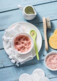 O corpo Himalaia cor-de-rosa caseiro do óleo de sal e de coco esfrega em um fundo azul, vista superior Beleza, conceito dos cuida foto de stock O corpo Himalaia cor-de-rosa caseiro do óleo de sal e de coco esfrega em um fundo azul, vista superior Beleza, conceito dos cuida foto de stock