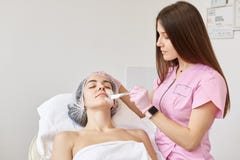 O Cosmetologist aplica o creme hidratando com a escova profissional na cara dos clientes, saindo das pinceladas brancas Mulher qu imagem de stock royalty free O Cosmetologist aplica o creme hidratando com a escova profissional na cara dos clientes, saindo das pinceladas brancas Mulher qu imagem de stock royalty free