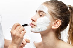O Cosmetologist aplica-se com uma m?scara cosm?tica branca da escova na cara da menina moreno nova imagens de stock royalty free O Cosmetologist aplica-se com uma m?scara cosm?tica branca da escova na cara da menina moreno nova imagens de stock royalty free