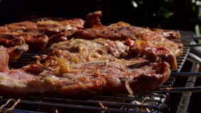 O cozinheiro coloca o bife do cordeiro com os tenazes de brasa de um metal O cozinheiro coloca o bife do cordeiro com os tenazes de brasa de um metal