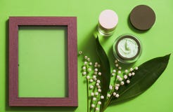 o creme e o lírio cosméticos do vale florescem em um fundo verde fotos de stock o creme e o lírio cosméticos do vale florescem em um fundo verde fotos de stock