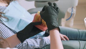 O dentista steadic disparado lento-movimento da mulher do close-up realiza nas mãos um modelo dos dentes humanos, mostra seu paci vídeos de arquivo O dentista steadic disparado lento-movimento da mulher do close-up realiza nas mãos um modelo dos dentes humanos, mostra seu paci vídeos de arquivo