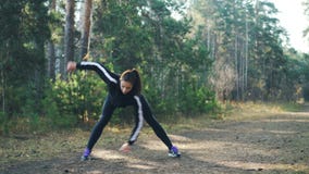 O desportista novo atrativo está fazendo esportes no parque no dia ensolarado do outono que veste o fato de esporte preto moderno video estoque O desportista novo atrativo está fazendo esportes no parque no dia ensolarado do outono que veste o fato de esporte preto moderno video estoque