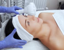 O doutor-cosmetologist faz o procedimento Cryotherapy da pele facial de um bonito, jovem mulher em um salão de beleza fotografia de stock O doutor-cosmetologist faz o procedimento Cryotherapy da pele facial de um bonito, jovem mulher em um salão de beleza fotografia de stock