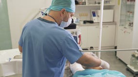 O doutor em luvas est?reis desinfeta o p? paciente e prepara ferramentas m?dicas antes da cirurgia da veia varicosa video estoque O doutor em luvas est?reis desinfeta o p? paciente e prepara ferramentas m?dicas antes da cirurgia da veia varicosa video estoque