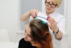 O doutor examina o escalpe um dispositivo especial com uma lâmpada UV foto de stock O doutor examina o escalpe um dispositivo especial com uma lâmpada UV foto de stock
