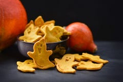 O fantasma assustador amarelo deu forma a cookies de Dia das Bruxas com as abóboras alaranjadas no fundo escuro foto de stock O fantasma assustador amarelo deu forma a cookies de Dia das Bruxas com as abóboras alaranjadas no fundo escuro foto de stock
