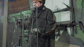 O ferreiro no vestuário de proteção faz uma cerca forjada video estoque O ferreiro no vestuário de proteção faz uma cerca forjada video estoque