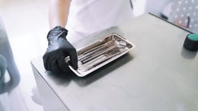O fim acima das mãos do dentista abre o grupo com os instrumentos dentais esterilizados, movimento lento video estoque O fim acima das mãos do dentista abre o grupo com os instrumentos dentais esterilizados, movimento lento video estoque