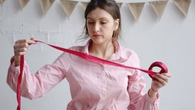 O florista da mulher profissional desenrola a fita vermelha foto de stock O florista da mulher profissional desenrola a fita vermelha foto de stock