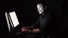 O hacker na máscara corta o programa a extorsão digital obtém o acesso à outra informação do ` s dos povos Computador video estoque O hacker na máscara corta o programa a extorsão digital obtém o acesso à outra informação do ` s dos povos Computador video estoque