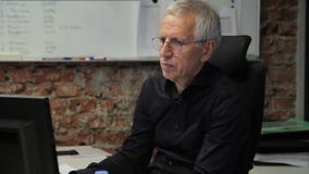 O homem adulto está trabalhando atentamente no escritório na frente do computador O homem adulto está trabalhando atentamente no escritório na frente do computador