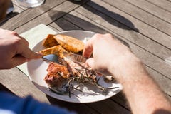 O homem come um bife cozinhado com os vegetais na grade imagem de stock royalty free O homem come um bife cozinhado com os vegetais na grade imagem de stock royalty free