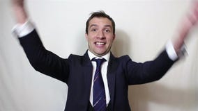 O homem de negócios novo considerável expressa ativamente a alegria, faz um gesto com sua mão e di-lo ‘sim ‘ video estoque O homem de negócios novo considerável expressa ativamente a alegria, faz um gesto com sua mão e di-lo ‘sim ‘ video estoque