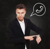 O homem de negócios aponta no relógio, hora de chamar imagem de stock O homem de negócios aponta no relógio, hora de chamar imagem de stock