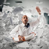 O homem de negócios com boia salva-vidas afunda-se entre folhas no escritório foto de stock royalty free O homem de negócios com boia salva-vidas afunda-se entre folhas no escritório foto de stock royalty free