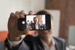 O homem de negócios de sorriso faz a imagem do autorretrato no escritório imagens de stock royalty free O homem de negócios de sorriso faz a imagem do autorretrato no escritório imagens de stock royalty free