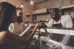 O homem de sorriso do barista dá a uma menina sua ordem fotos de stock O homem de sorriso do barista dá a uma menina sua ordem fotos de stock