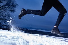 O homem do atleta está correndo durante a parte externa do treinamento do inverno no tempo frio da neve foto de stock O homem do atleta está correndo durante a parte externa do treinamento do inverno no tempo frio da neve foto de stock