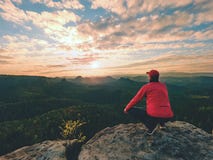O homem do caminhante toma um resto no pico de montanha Homem colocado na cimeira, foto de stock O homem do caminhante toma um resto no pico de montanha Homem colocado na cimeira, foto de stock