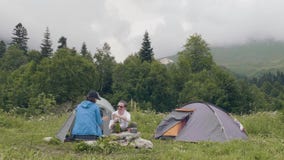O homem e a mulher que descansam na barraca e na montanha de acampamento ajardinam o fundo filme O homem e a mulher que descansam na barraca e na montanha de acampamento ajardinam o fundo filme