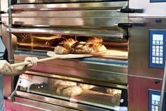 O homem está cozendo o pão no forno imagens de stock royalty free O homem está cozendo o pão no forno imagens de stock royalty free