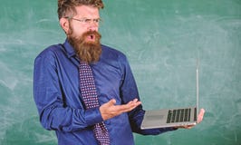 O homem farpado do professor confundiu o trabalho com o fundo moderno do quadro do portátil A expressão confusa do professor do m foto de stock royalty free O homem farpado do professor confundiu o trabalho com o fundo moderno do quadro do portátil A expressão confusa do professor do m foto de stock royalty free