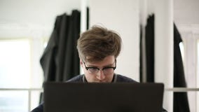O homem inteligente que veste espetáculos trabalha no computador no estúdio video estoque O homem inteligente que veste espetáculos trabalha no computador no estúdio video estoque