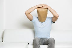O homem anônimo miserável com cabeça cobriu o assento no sofá. fotos de stock royalty free O homem anônimo miserável com cabeça cobriu o assento no sofá. fotos de stock royalty free