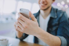 O homem novo ou o freelancer atrativo com móbil estão sentando-se no café e no café bebendo imagens de stock O homem novo ou o freelancer atrativo com móbil estão sentando-se no café e no café bebendo imagens de stock