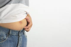 O homem que toca no seu barrigudo gordo da barriga no fundo branco para imagem de stock royalty free O homem que toca no seu barrigudo gordo da barriga no fundo branco para imagem de stock royalty free