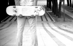 O indivíduo está estando no parque com um skate em suas mãos fotos de stock O indivíduo está estando no parque com um skate em suas mãos fotos de stock