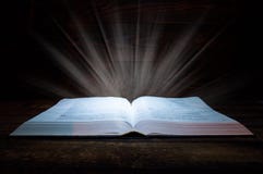 O livro grande das mentiras da B?blia em uma tabela de madeira Na obscuridade Uma luz brilha no livro de cima de A luz sai do liv foto de stock royalty free O livro grande das mentiras da B?blia em uma tabela de madeira Na obscuridade Uma luz brilha no livro de cima de A luz sai do liv foto de stock royalty free