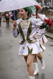 O majorette novo sorri sob o guarda-chuva branco na parada de carnaval, Fotografia de Stock Royalty Free O majorette novo sorri sob o guarda-chuva branco na parada de carnaval, Fotografia de Stock Royalty Free