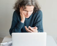 O meio envelheceu a mulher frustrado com smartphone e computador fotografia de stock O meio envelheceu a mulher frustrado com smartphone e computador fotografia de stock
