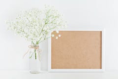 O modelo da moldura para retrato decorado floresce no vaso na mesa de trabalho branca com espaço limpo para o texto e projeta seu imagem de stock royalty free O modelo da moldura para retrato decorado floresce no vaso na mesa de trabalho branca com espaço limpo para o texto e projeta seu imagem de stock royalty free