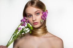 O modelo f?mea novo bonito com olhos azuis, pele perfeita com as flores no ombro, seu pesco?o ? envolvido no cabelo foto de stock royalty free O modelo f?mea novo bonito com olhos azuis, pele perfeita com as flores no ombro, seu pesco?o ? envolvido no cabelo foto de stock royalty free