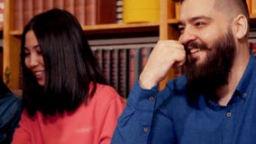 O moderno senta e ajusta sua barba na tabela com seus amigos favoritos em um café bonito O moderno senta e ajusta sua barba na tabela com seus amigos favoritos em um café bonito