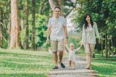 O pai, a mãe e o bebê andam ao longo do parque imagens de stock O pai, a mãe e o bebê andam ao longo do parque imagens de stock
