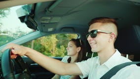 O par novo feliz está viajando pelo carro Um homem conduz um carro, a esposa senta emoções próximas, positivas video estoque O par novo feliz está viajando pelo carro Um homem conduz um carro, a esposa senta emoções próximas, positivas video estoque