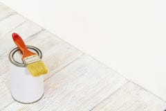 O pincel e pode, escova de pintura e a cor branca no assoalho de madeira imagem de stock O pincel e pode, escova de pintura e a cor branca no assoalho de madeira imagem de stock