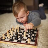O rapaz pequeno joga a xadrez que encontra-se no assoalho imagens de stock royalty free O rapaz pequeno joga a xadrez que encontra-se no assoalho imagens de stock royalty free