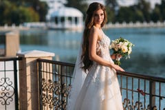 O retrato da noiva nova com os cabelos longos que guardam seu ramalhete do casamento inclui as rosas brancas e as outras flores B Fotos de Stock O retrato da noiva nova com os cabelos longos que guardam seu ramalhete do casamento inclui as rosas brancas e as outras flores B Fotos de Stock