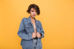 O retrato de uma mulher moreno bonita vestiu-se no revestimento da sarja de Nimes imagem de stock O retrato de uma mulher moreno bonita vestiu-se no revestimento da sarja de Nimes imagem de stock