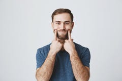 O retrato horizontal do homem descontentado e desagradado com barba vestiu-se ocasionalmente, olhando a câmera com seus olhos azu fotos de stock O retrato horizontal do homem descontentado e desagradado com barba vestiu-se ocasionalmente, olhando a câmera com seus olhos azu fotos de stock